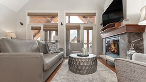 A modern living room with a fireplace, leather sofa, and a television.