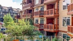 Un edificio de varios pisos con balcones, piscina y un tobogán pequeño.