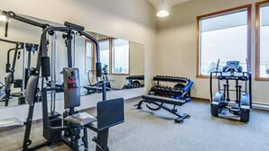 Et fitnessrum med forskellig træningsudstyr, herunder en bænkpres, håndvægte og et squat rack.