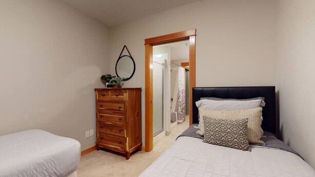 A bedroom with two beds, a wooden dresser, and a mirror.