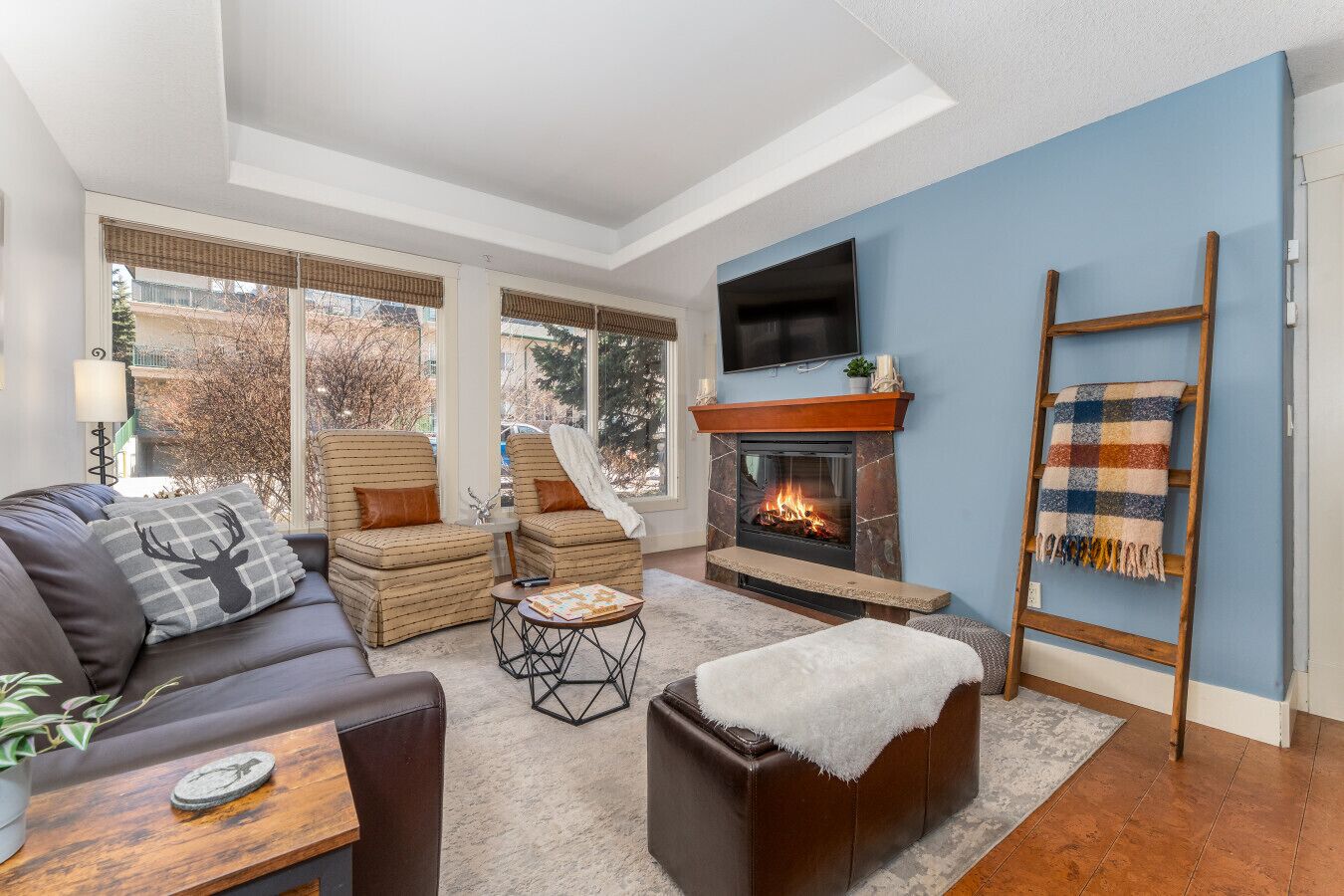 A cozy living room with a fireplace, a sofa, a coffee table, and a TV mounted on the wall.
