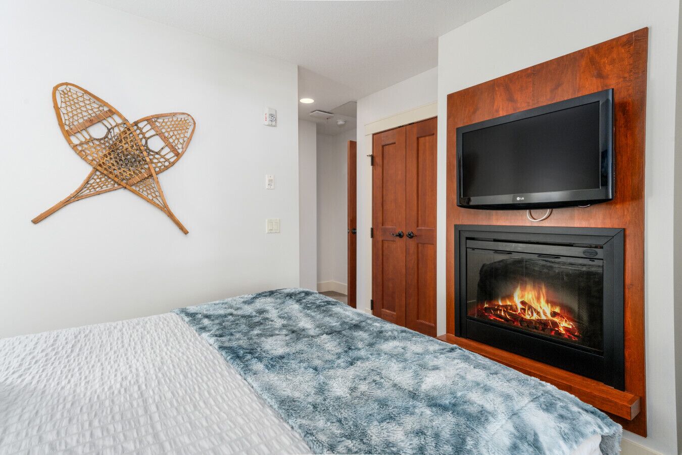 Ein Schlafzimmer mit einem Bett, einem Fernseher über einem Kamin und einem Holzschrank.