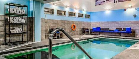 An indoor swimming pool with a clear water view, a lifebuoy, and a blue seating area.