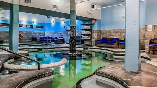 A spa area with a central hot tub, seating areas, and a water feature. - AURORA NIGHTS -  COZY LIVING -  SPA, POOL & HOT TUB (Canmore)