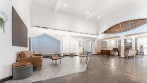 A spacious lobby with a high ceiling, a staircase, and a seating area with a sofa and ottoman. - BLUE BIRD SKIES - MOUNTAIN VIEWS - GYM & SECURE PARKING (Canmore)