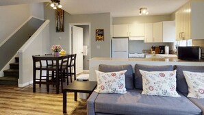 Una sala de estar moderna con un sofá, una mesa de comedor y una cocina al fondo.