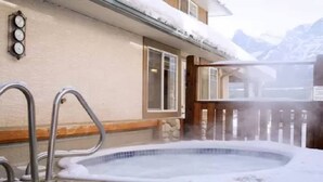 Un jacuzzi con cubierta de madera y pared de piedra.
