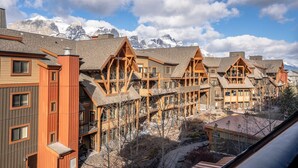 Ein Resort mit mehreren Holzbauten, großen Fenstern und Blick auf schneebedeckte Berge.