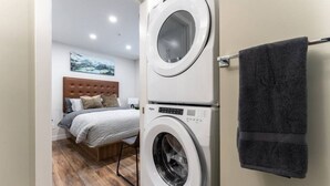 Una habitación de hotel con una cama, lavadora y un perchero.
