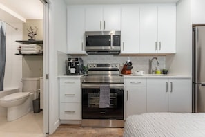 Kitchen features stainless steel appliances, white cabinetry, and a tiled backsplash.