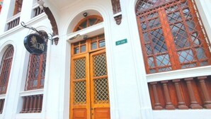 A building with a large wooden door, arched windows, and a sign with a hand symbol. - Hotel Inti Quito (Quito)