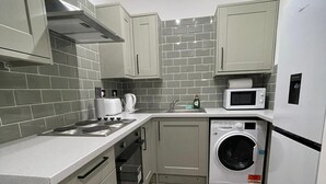A compact kitchen with grey cabinets, a microwave, a washing machine, and a stove.