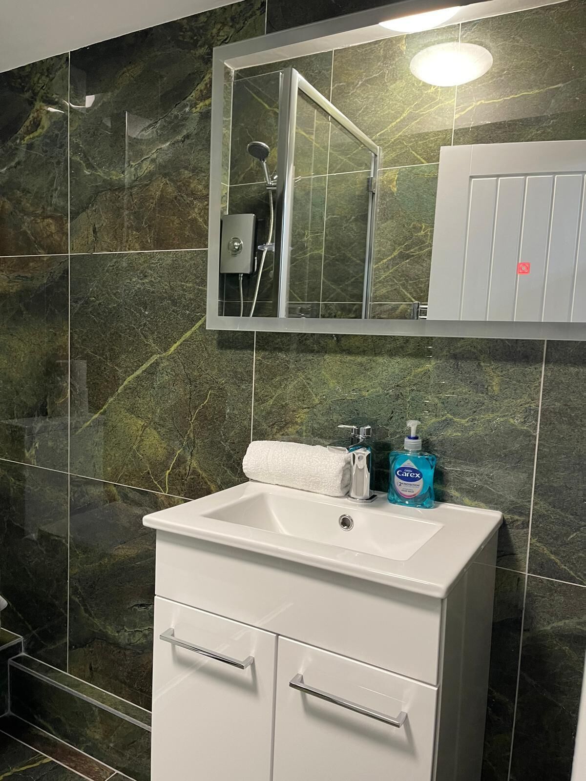 A bathroom with a white sink, a mirror, and a shower enclosure.