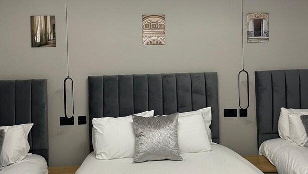 A hotel room with a large bed, two bedside tables, and a modern ceiling light fixture.