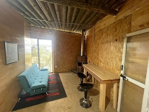 Une pièce au décor rustique, avec un canapé, un coin bar et une grande fenêtre.