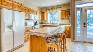 A kitchen with wooden cabinets, a refrigerator, a microwave, and a dining area with chairs. - HOT TUB, Eagle Crest Condo on Golf Course, DOGS OK (Redmond)