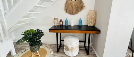 A staircase with white railings, a black table with decorative items, a woven basket, and a potted plant.