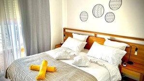 Een hotelkamer met een groot bed, een houten hoofdeinde en een nachtkastje met een lamp.