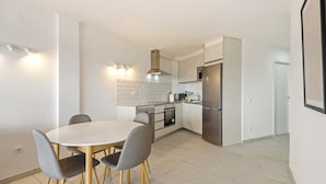 Una cocina moderna con comedor, que incluye una mesa redonda, sillas y electrodomésticos integrados.