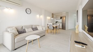 Una sala de estar moderna con un sofá, una mesita y un comedor con sillas.