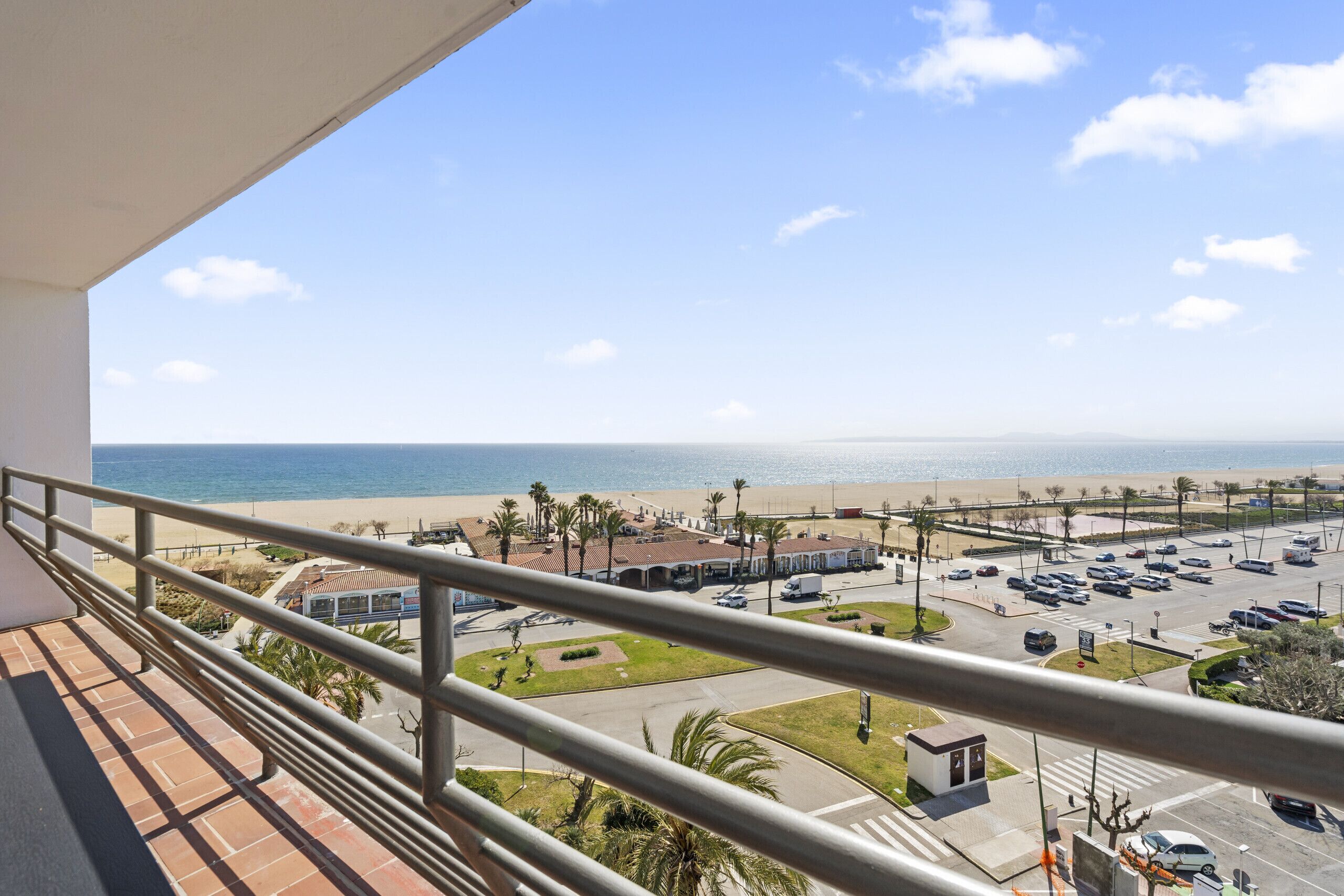 Ein Balkon mit Blick auf einen Strand, einen Parkplatz und Gebäude.