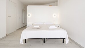 Un dormitorio moderno con una cama grande, mesitas de noche e iluminación en la pared.