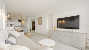 Una sala de estar moderna con un sofá grande, una mesita redonda y un televisor montado en un mueble.