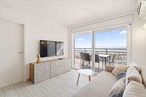 A modern living room with a flat-screen TV, a sofa, and a balcony with outdoor seating.