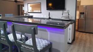 A modern kitchen with a central island, a built-in TV, and a refrigerator. - Spacious, private retreat -  hot tub, firepit, pool table, dry sauna, patio (Oak Ridge)