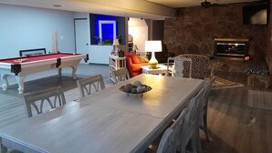 A spacious living room with a pool table, a dining area with a table and chairs, and a cozy seating area with a sofa and a patterned armchair. - Spacious, private retreat -  hot tub, firepit, pool table, dry sauna, patio (Oak Ridge)