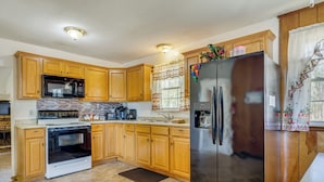A kitchen with wooden cabinets, a stainless steel refrigerator, a microwave, and a stove. - 1 Mi to MCAS New River: Peaceful Home w/ Patio (Jacksonville)