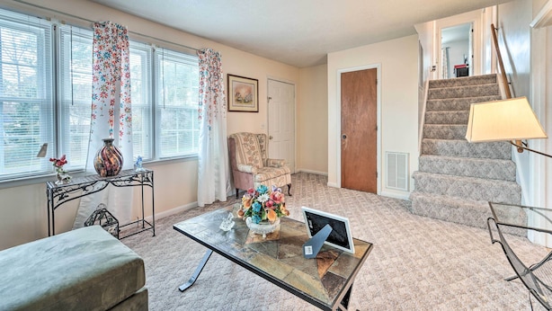 A living room with a glass coffee table, a sofa, a chair, a staircase, and a door. - 1 Mi to MCAS New River: Peaceful Home w/ Patio (Jacksonville)