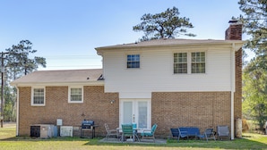 A two-story house with a brick exterior, a front door, and a small porch area with outdoor furniture. - 1 Mi to MCAS New River: Peaceful Home w/ Patio (Jacksonville)