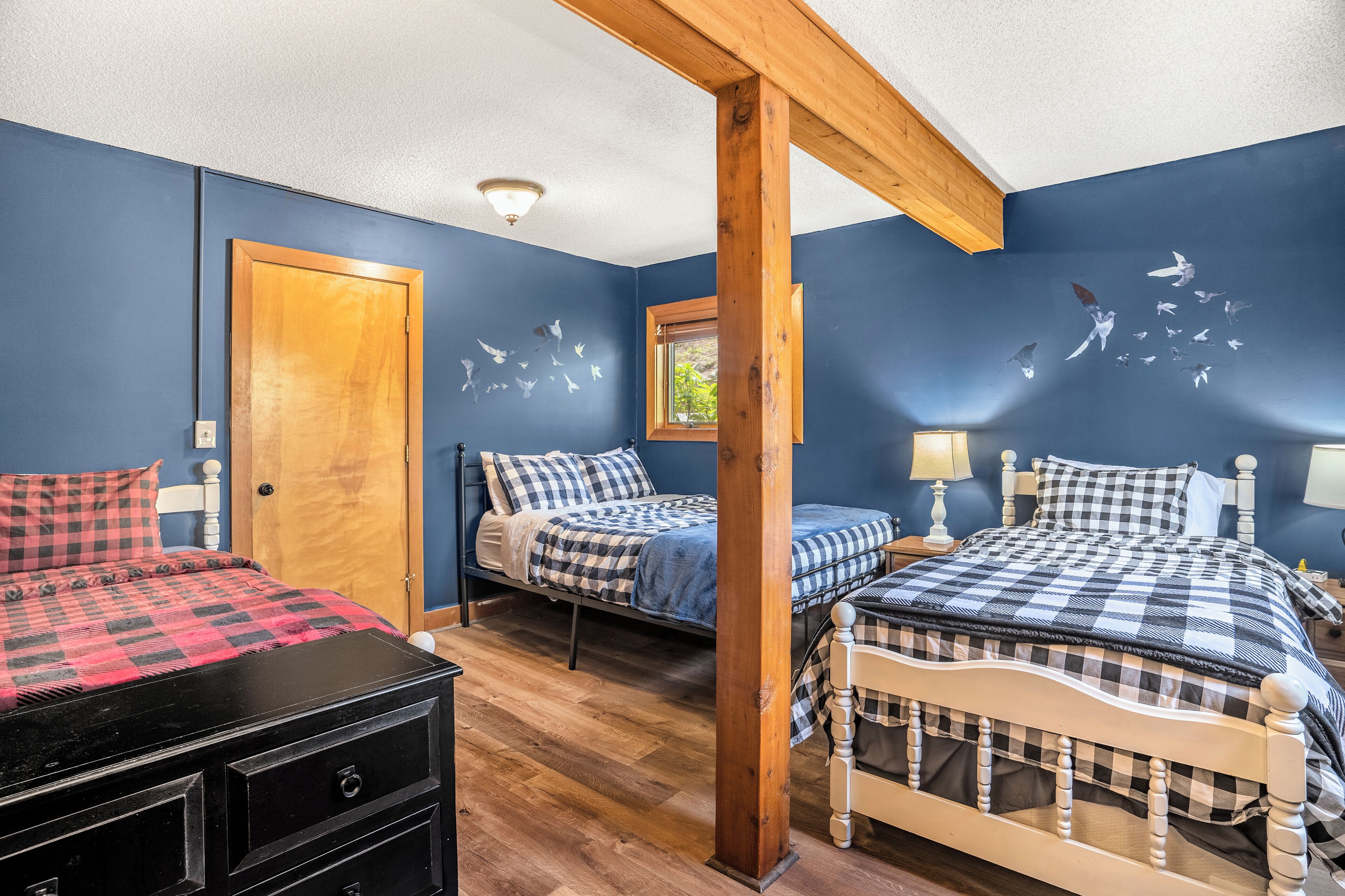 A bedroom with two beds, a wooden wardrobe, and a window.