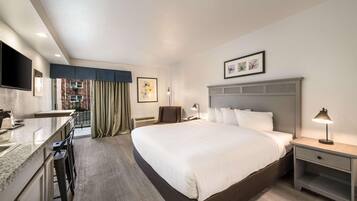 A hotel room with a bed, a desk, a chair, a TV, and a window with curtains.