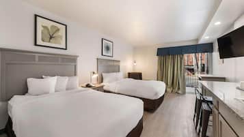 A hotel room with two beds, a desk, a chair, a TV, and a window with curtains.