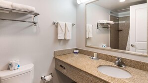 Un baño con lavamanos, espejo, toallero y retrete.