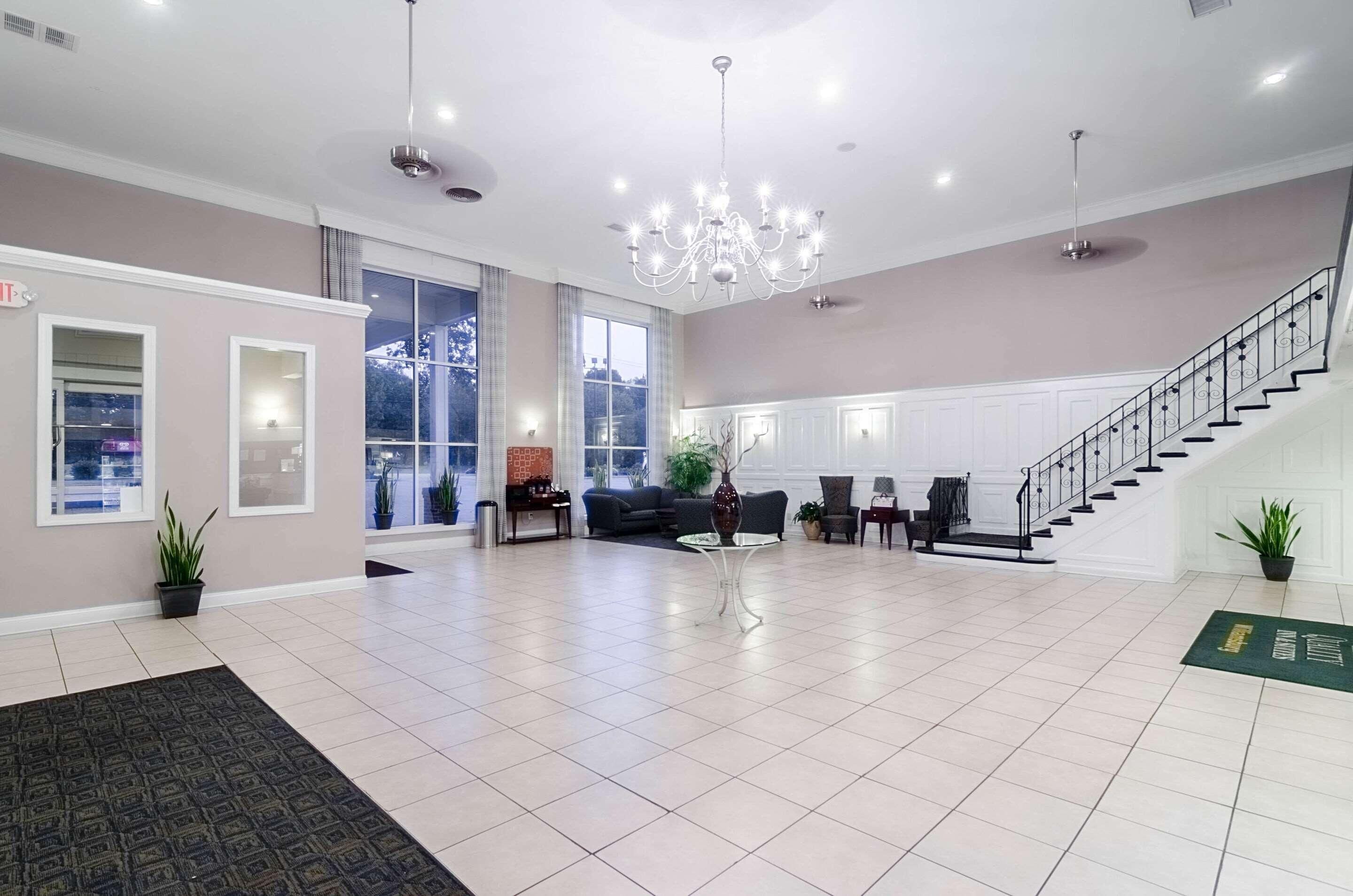 A spacious lobby with a chandelier, a staircase, and a reception desk.
