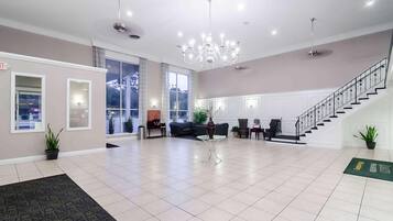 A spacious lobby with a chandelier, a staircase, and a reception desk.