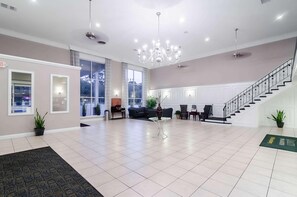 A spacious lobby with a chandelier, a staircase, and a reception desk. - Suburban Williamsburg (Williamsburg)