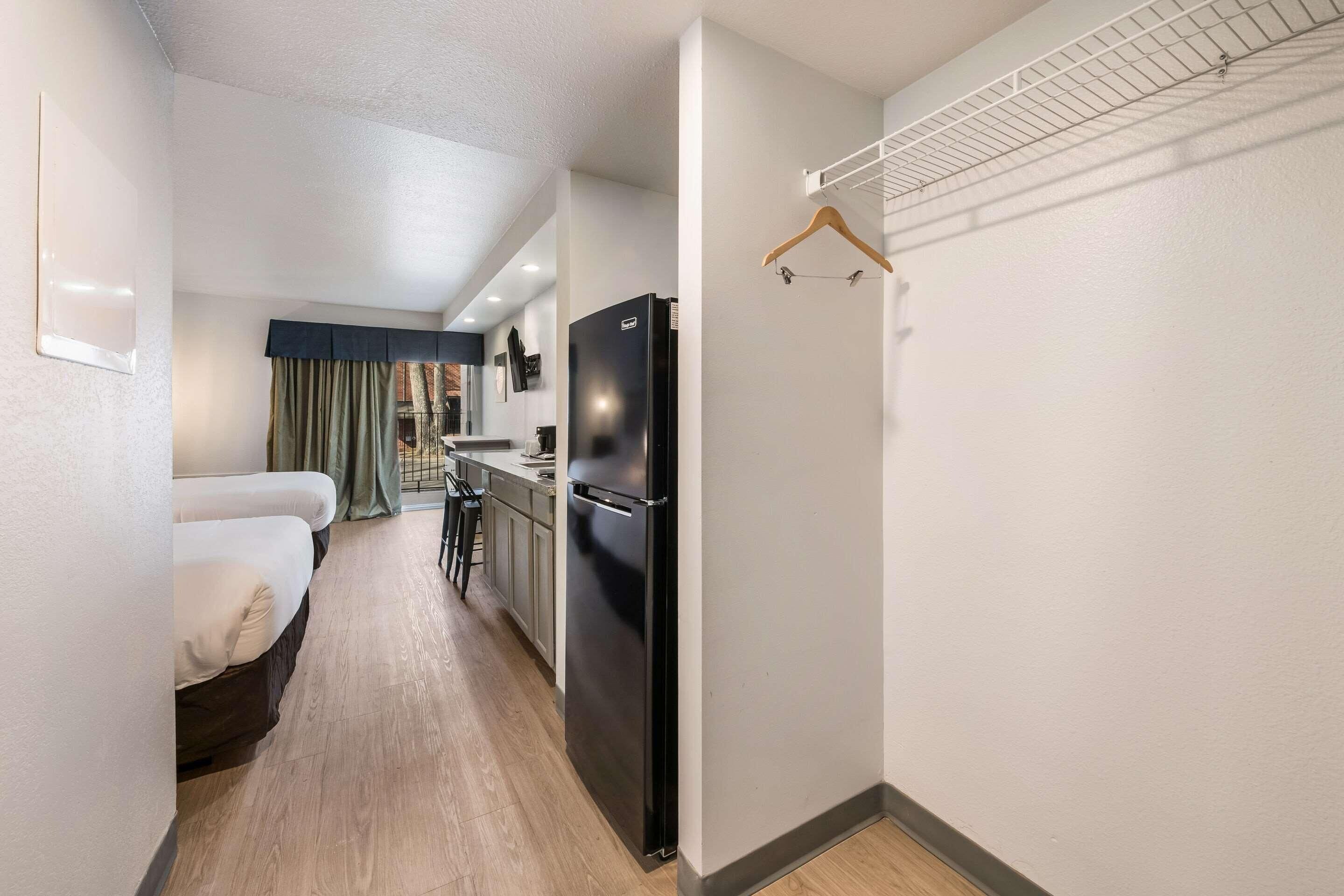 A compact hotel room with a bed, a kitchenette, and a small dining area.