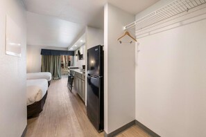 Una habitación de hotel compacta con cama, kitchenette y un pequeño comedor.