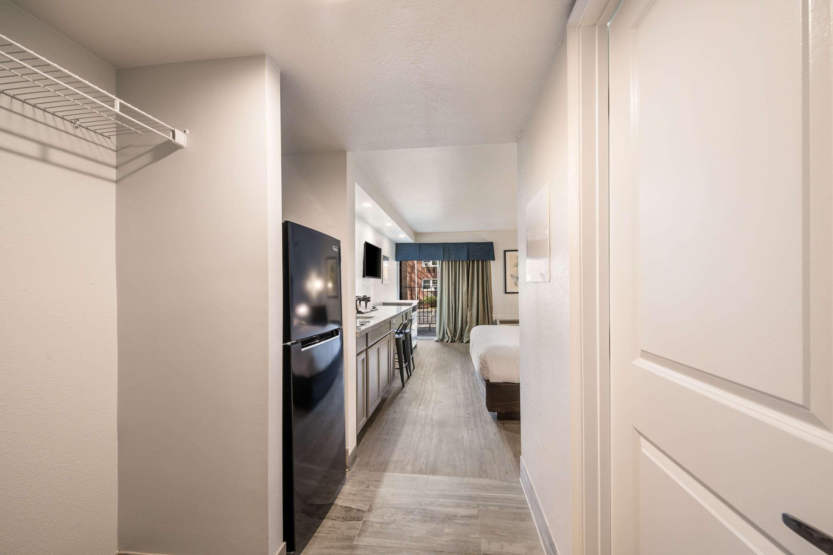 A hotel hallway with a kitchenette, a bed, and a view of the outside.