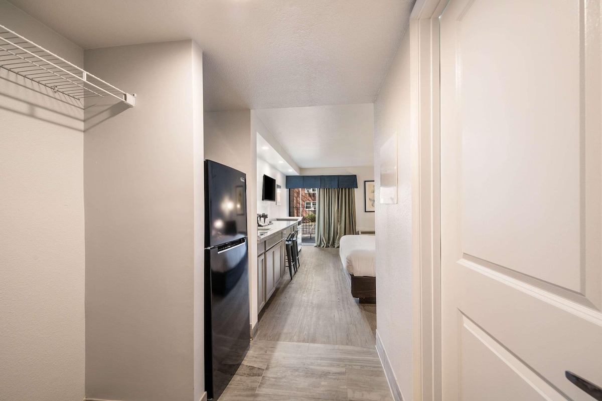 A hotel hallway with a kitchenette, a bed, and a view of the outside.