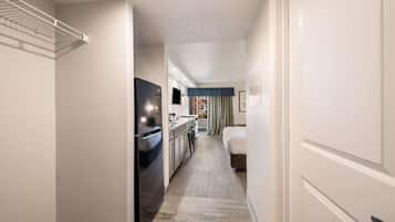 A hotel hallway with a kitchenette, a bed, and a view of the outside.