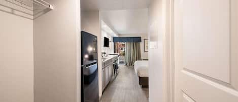 Un pasillo de hotel con kitchenette, una cama y vistas al exterior.