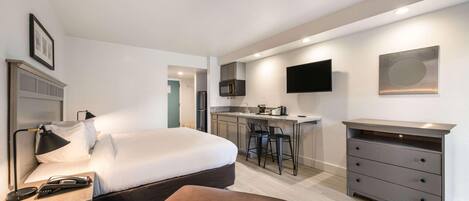 Une chambre d’hôtel moderne équipée d’un lit, d’un bureau, d’une chaise et d’une kitchenette.