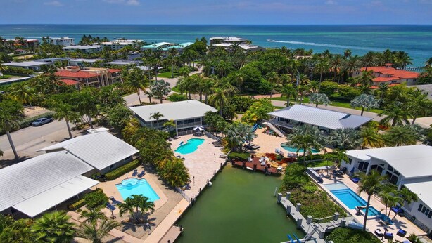 Un resort con varias piscinas, palmeras y vistas al océano.