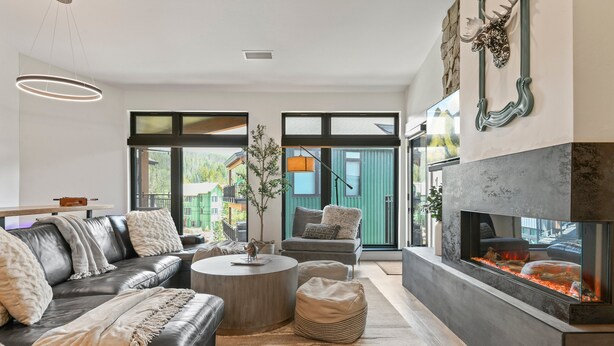 A modern living room with a fireplace, leather sofa, and a view of the outdoors.