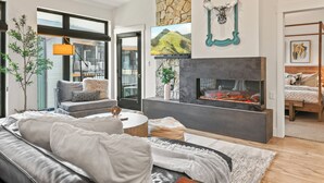 A modern living room with a fireplace, a sofa, a coffee table, and a TV mounted on the wall.